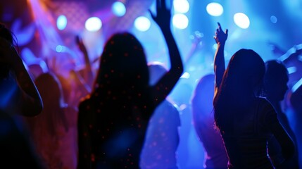 a group of people standing in front of a stage with their hands up in the air and lights on..