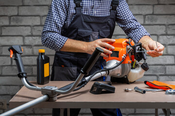 Man repair of petrol mowers. Mechanic working, repairing strimmer.