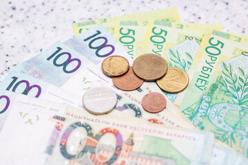 Saving money handling a stack of green banknotes and pink coins on a table