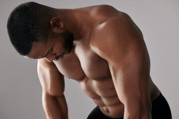 Body muscle, fitness and tired black man in studio with abdomen for exercise or health isolated on...