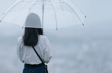 雨の中で傘をさす女性の後ろ姿