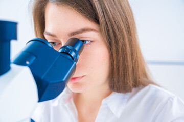 young woman in a scientific laboratory working with a microscope