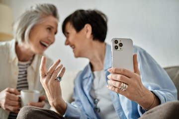 A loving mature lesbian couple posing for selfies with a cellphone.