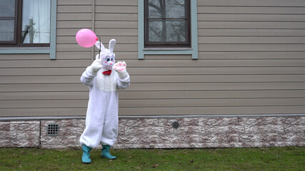 A man in a bunny costume with a pink balloon.