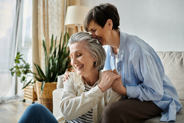 Two elderly women hugging tenderly on a cozy couch.