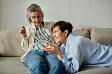 Two elderly women sit on a comfy couch, engrossed in a deep conversation.