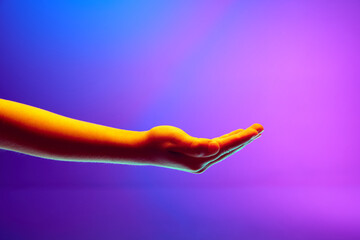 Kids hands gesturing with open palm against gradient blue purple background in neon light. Copy...