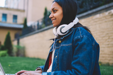 Happy afro american international student typing on laptop preparing for examination outdoors in...