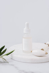 Mock up glass dropper bottle with liquid essence or serum on white marble podium on white background.