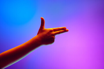 Kids hands gesturing against gradient blue purple background in neon light. Playful symbols of gun. Playing. Copy space for ad, text. Banner.