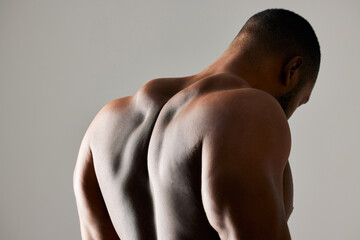 Back, closeup and man in studio with body health, strong for fitness and exercise in gym. Bodybuilder, sports and gray background with muscle of model for training, zoom for anatomy or growth