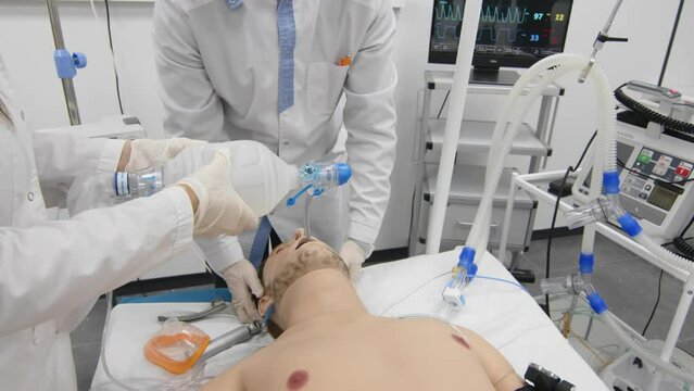 A medical mannequin is lying on a bed connected to the devices