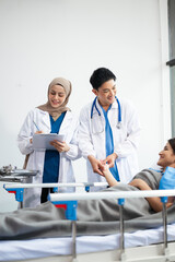 Obraz premium Hospital Ward Male and Male Professional Asian Doctors Talk with a Patient, Give Health Care Advice, Recommend Treatment Plan