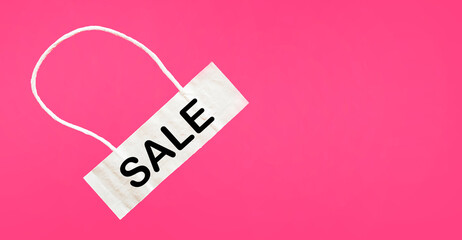 Light tag with the word Sale isolated on a pink background.