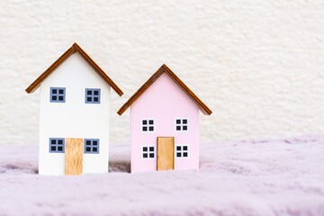 Two small wooden houses on mauve carpet. Real estate, architecture and housing concept.