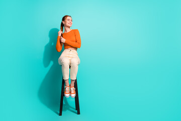Full length photo of positive woman wear crop top sit on chair look at offer empty space hold tail...
