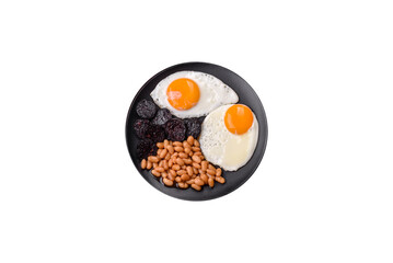 English breakfast with fried eggs, bacon, beans, tomatoes, spices and herbs