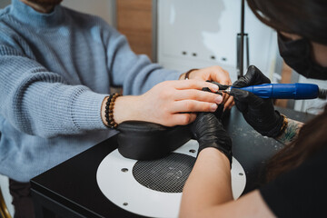 Professional manicure service at a nail salon using an electric nail drill for nail care and enhancement. Closeup work by a technician for a luxury beauty treatment