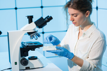 young female student studying biopsy samples in a cancer medical laboratory