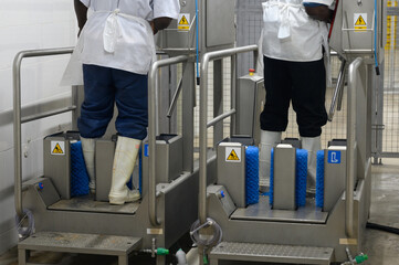 two workers at the Shoe Hygiene Station manually / automaticly washing, disinfecting and cleaning...