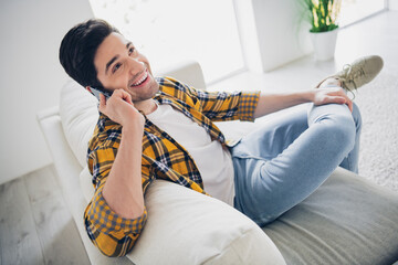 Photo of handsome cheerful guy dressed plaid shirt speaking modern gadget enjoying weekend indoors...