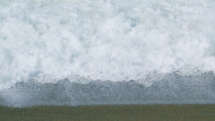 Multi-Colored Round Sea Sand On Sea Coast. Wave Leaves White Marks. Slow motion.