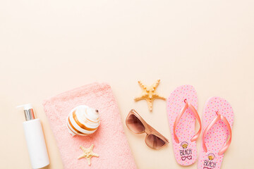 Summer holiday concept. Top view of beach towel, flip flop and sunscreen cream on table Top view...