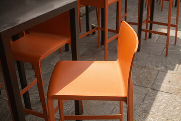 Orange plastic chair under the sunlight in a street cafe in Italy