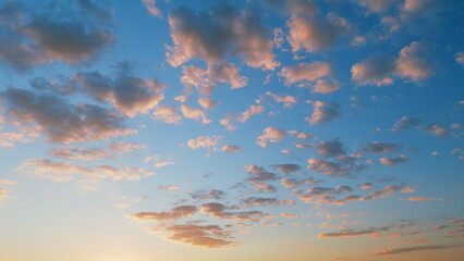 Orange to gold fluffy clouds rolling against vibrant blue sunset sky. Time lapse.