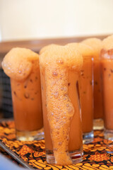 Iced Thai Tea with milk and foam on top in a glass.