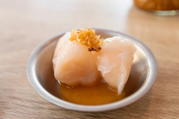 Steamed shrimp dumpling with sweet and sour sauce in a metal bowl on a wooden table.