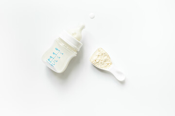 Bottle of milk for baby feeding with powdered milk in spoon