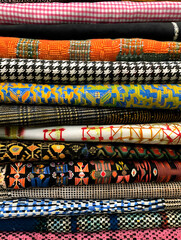 A stack of colorful fabric with a checkered pattern. The fabric is arranged in a way that it looks like a pile of clothes