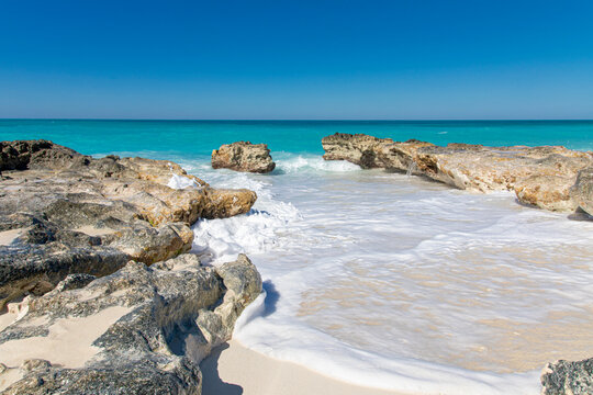 Waves crash along the rocks in the turquoise waters of the Caribbean Sea in the Bimini Islands, Bahamas.