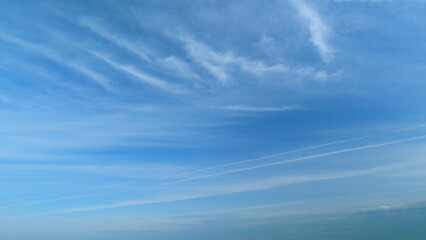 Clear blue sky with white wispy smoke clouds. Blue sky background with tiny stratus cirrus striped...