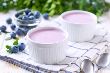 blueberry smoothie in a ceramic bowl with fresh blueberries on a white table, selective focus.