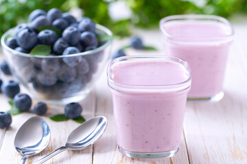 fresh natural homemade fruit yogurt in a glass jars with fresh blueberries on a light background,...