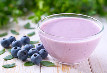 blueberry smoothie in a bowl with fresh blueberries on a white table, selective focus.