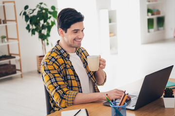 Photo of funky positive man wear checkered shirt communicating modern device drinking coffee house...