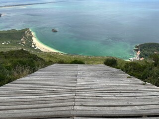 Wooden bridge descends into nature with panoramic sea view