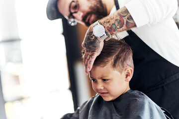 Barbershop, man and boy with haircut, comb and hairdresser treatment at salon with barber. Kid,...