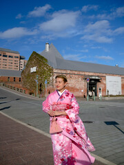 Woman in Traditional Pink Kimono Walking in Urban Japanese Setting with Historic Buildings