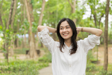 Portrait of asian woman breathing fresh air in a forest.Carefree asian girl smiling and enjoying...