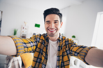 Photo of handsome flirty guy dressed plaid shirt recording video winking eye indoors room home house