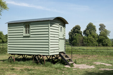 vintage green wooden shepherds hut in the countryside on a spring day