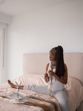 Thoughtful woman braiding hair