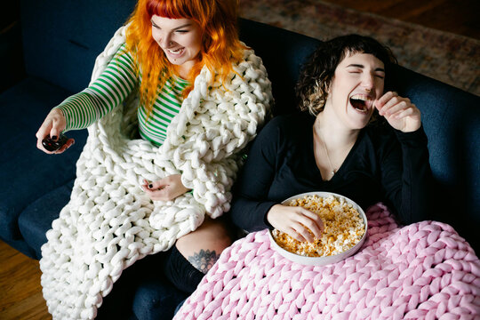Two Friends Laughing on the Couch Watching TV Together