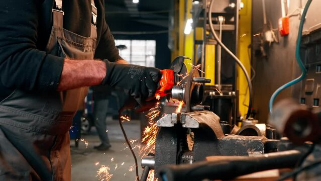 close-up of car mechanic working at a service station with an angle grinder from which sparks fly