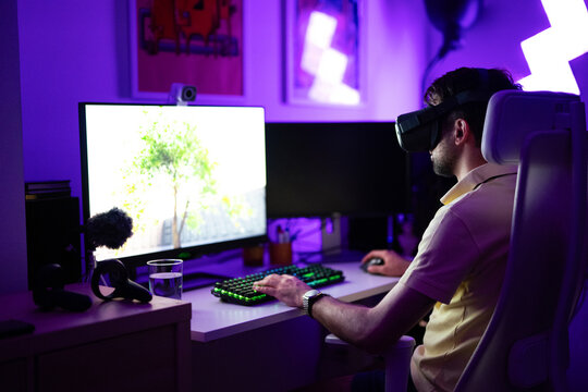 Young adult gamer playing using VR headset on computer PC