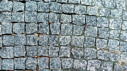 Cobbled stone path texture interlocking gray stones with grass details. Diagonal view of...